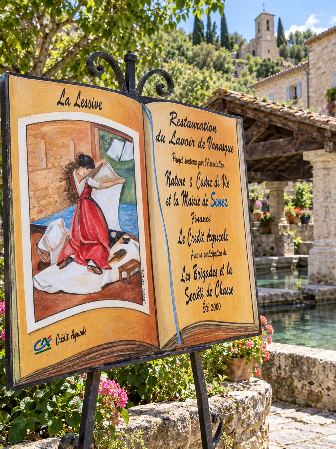 Panneau peint en forme de livre racontant la restauration d’un lavoir