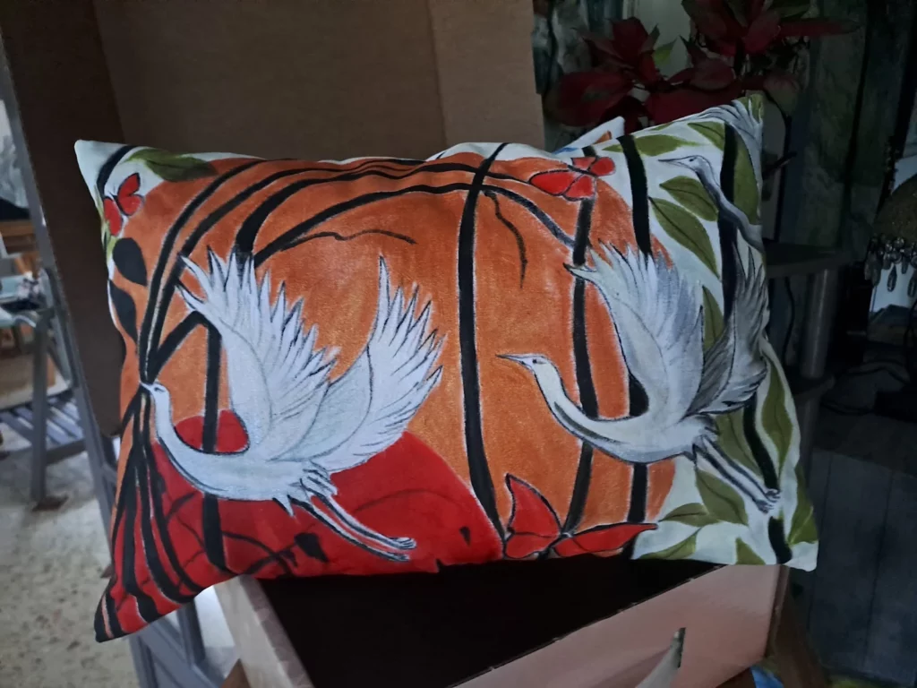Coussin artisanal avec deux grues blanches sur un fond orangé