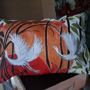 Coussin artisanal avec deux grues blanches sur un fond orangé